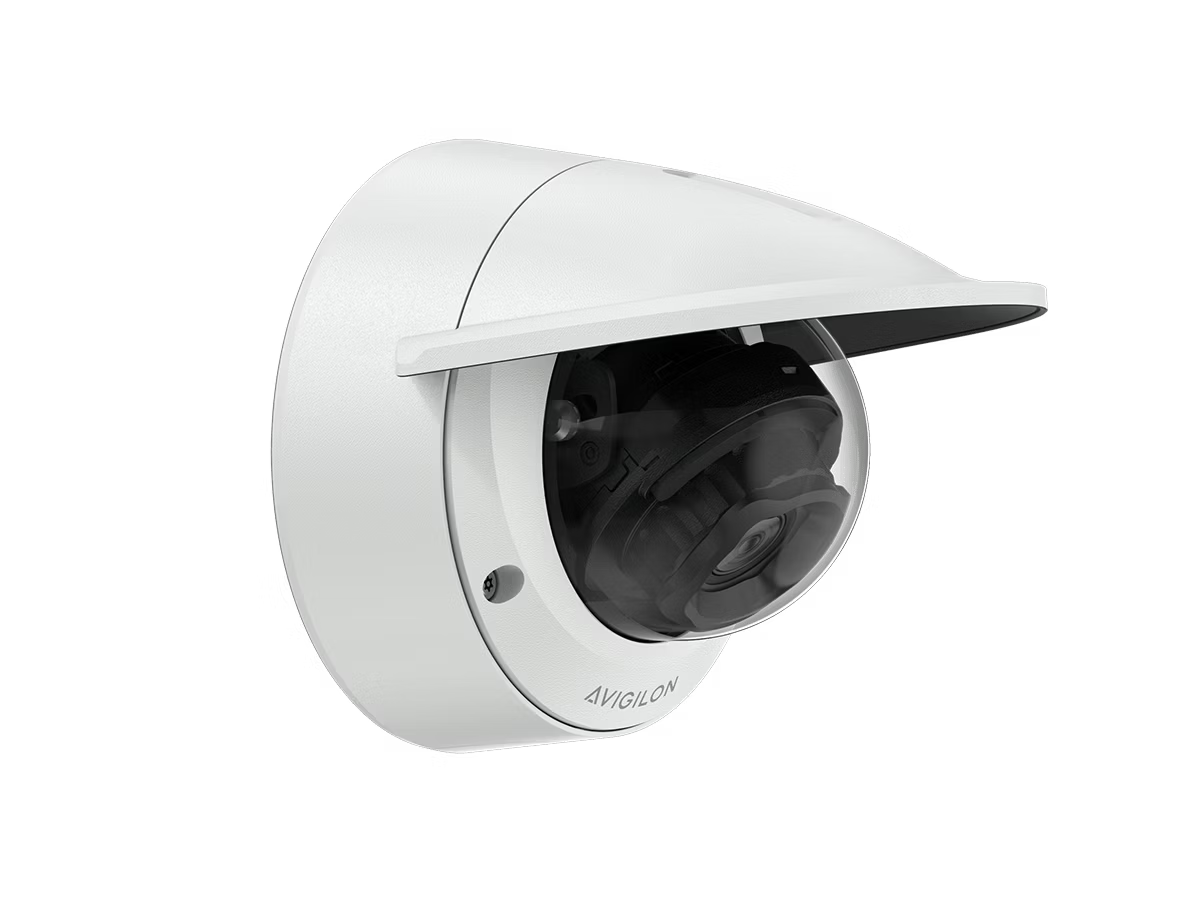 White surveillance camera with shield mounted on a wall.