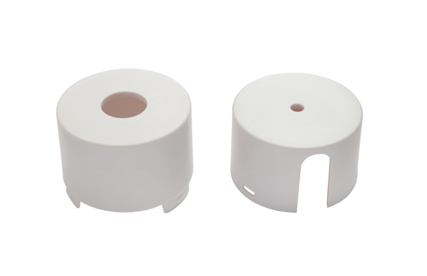 7000-00751601_com_03.png Twee witte, cilindrische kunststof delen met openingen.