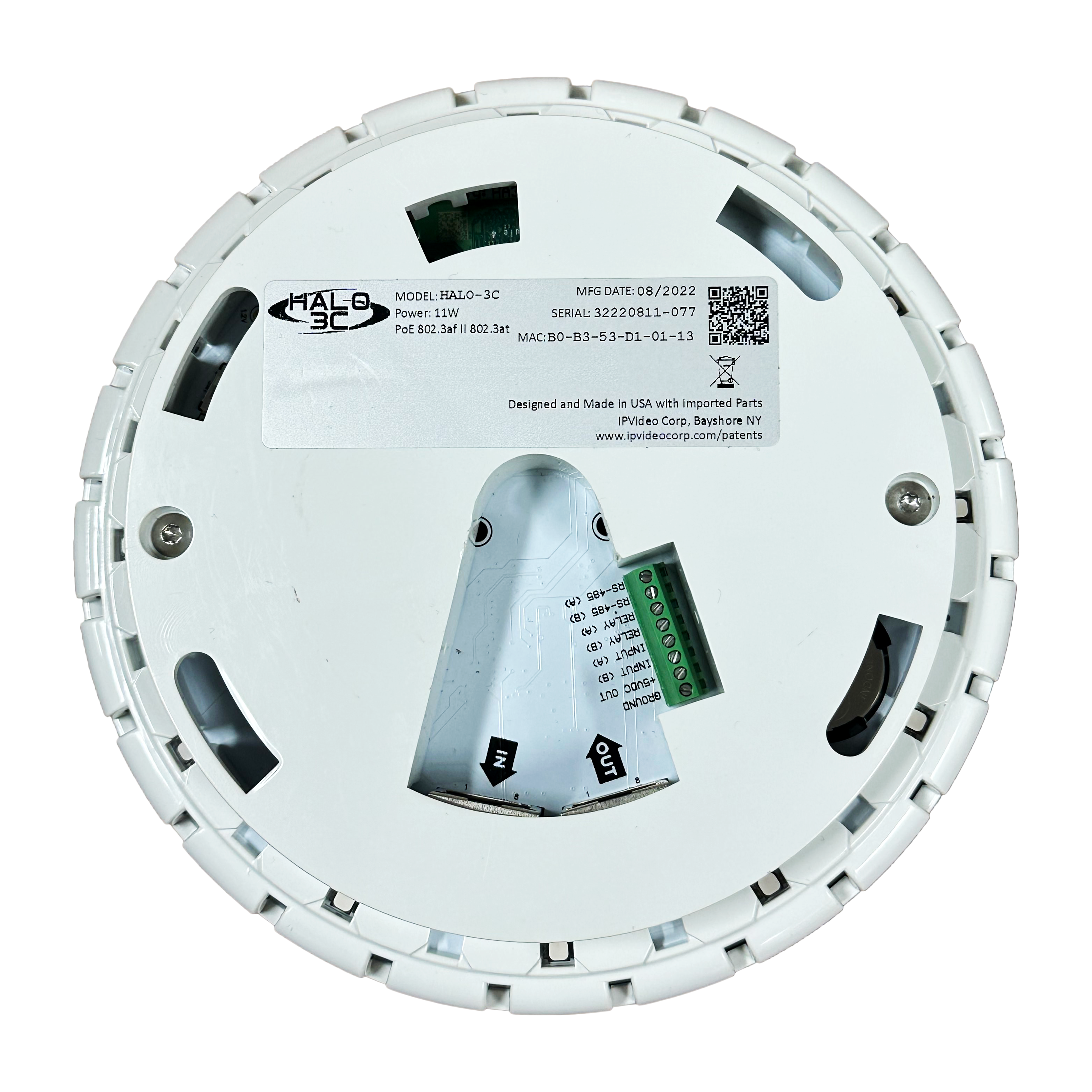 Onderkant van een rond elektronisch apparaat met label en aansluitingen.