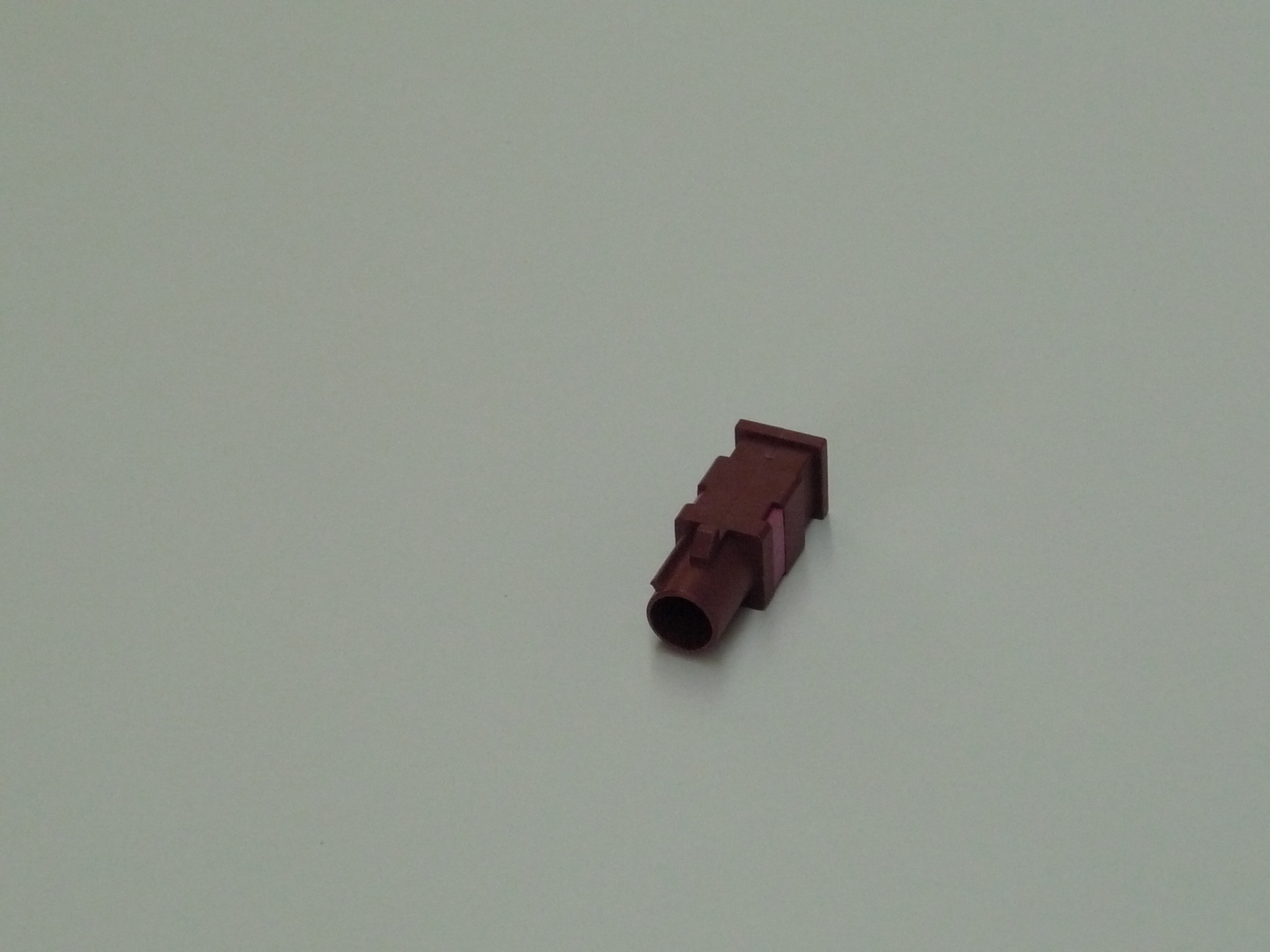 Rode kunststof connector op grijze achtergrond.
