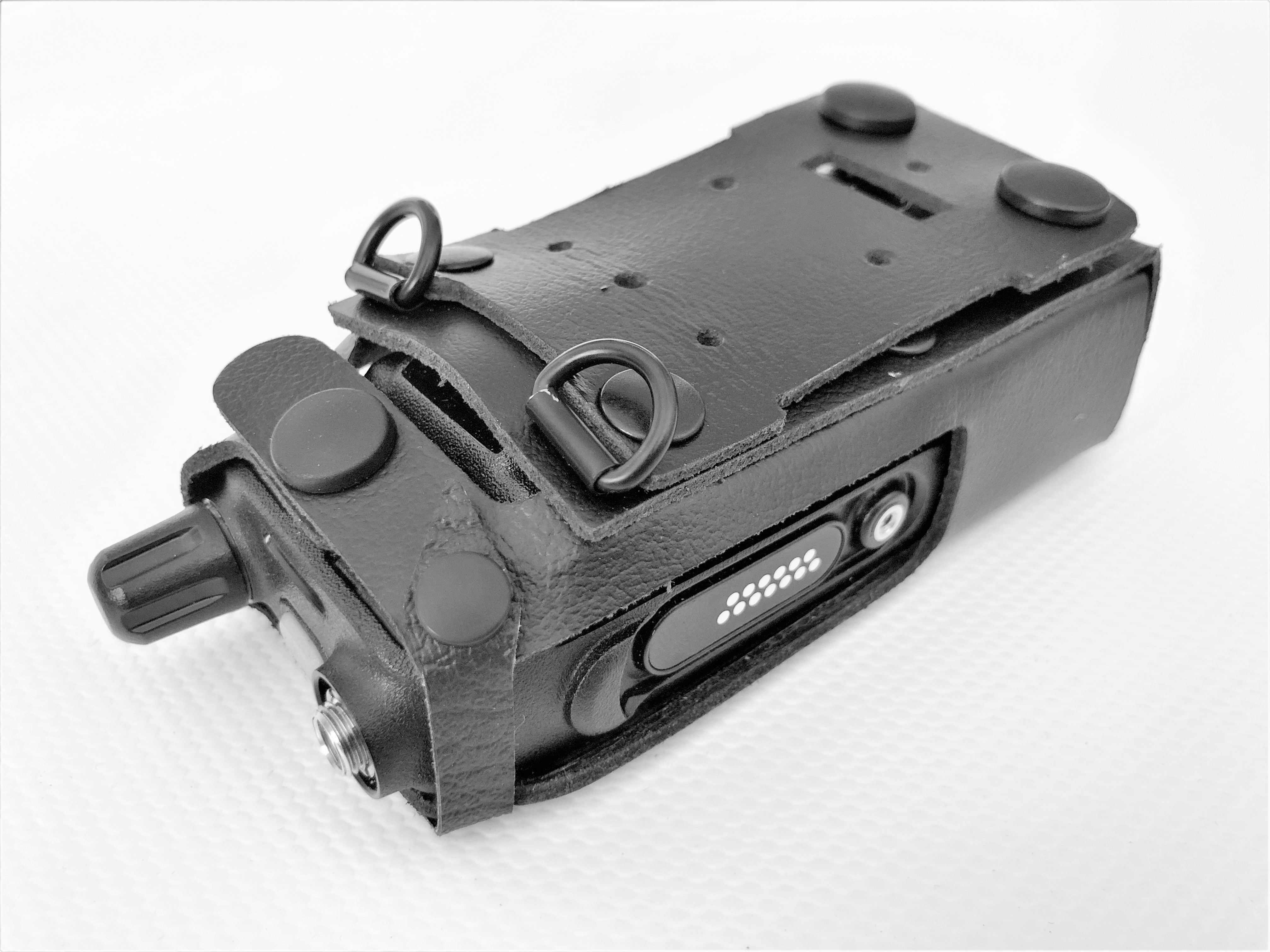 Étui en cuir noir avec clous métalliques et sangles sur surface plane.