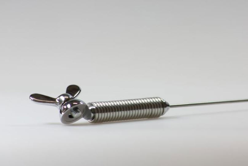 Metalen deurstop met verend ontwerp op een stevige ondergrond.