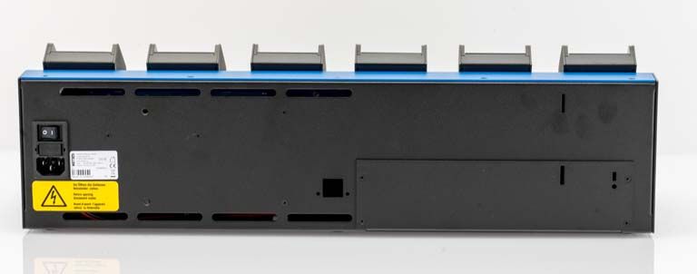 Achterkant van een elektronisch apparaat met schakelaar en waarschuwingslabel op gele sticker.