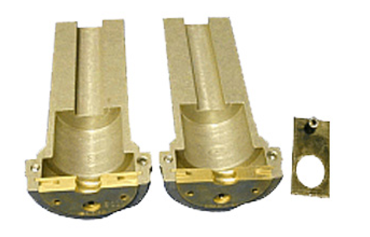Twee gouden metalen cilinders met rechthoekige bases, naast een rechthoekige metalen plaat met gat.