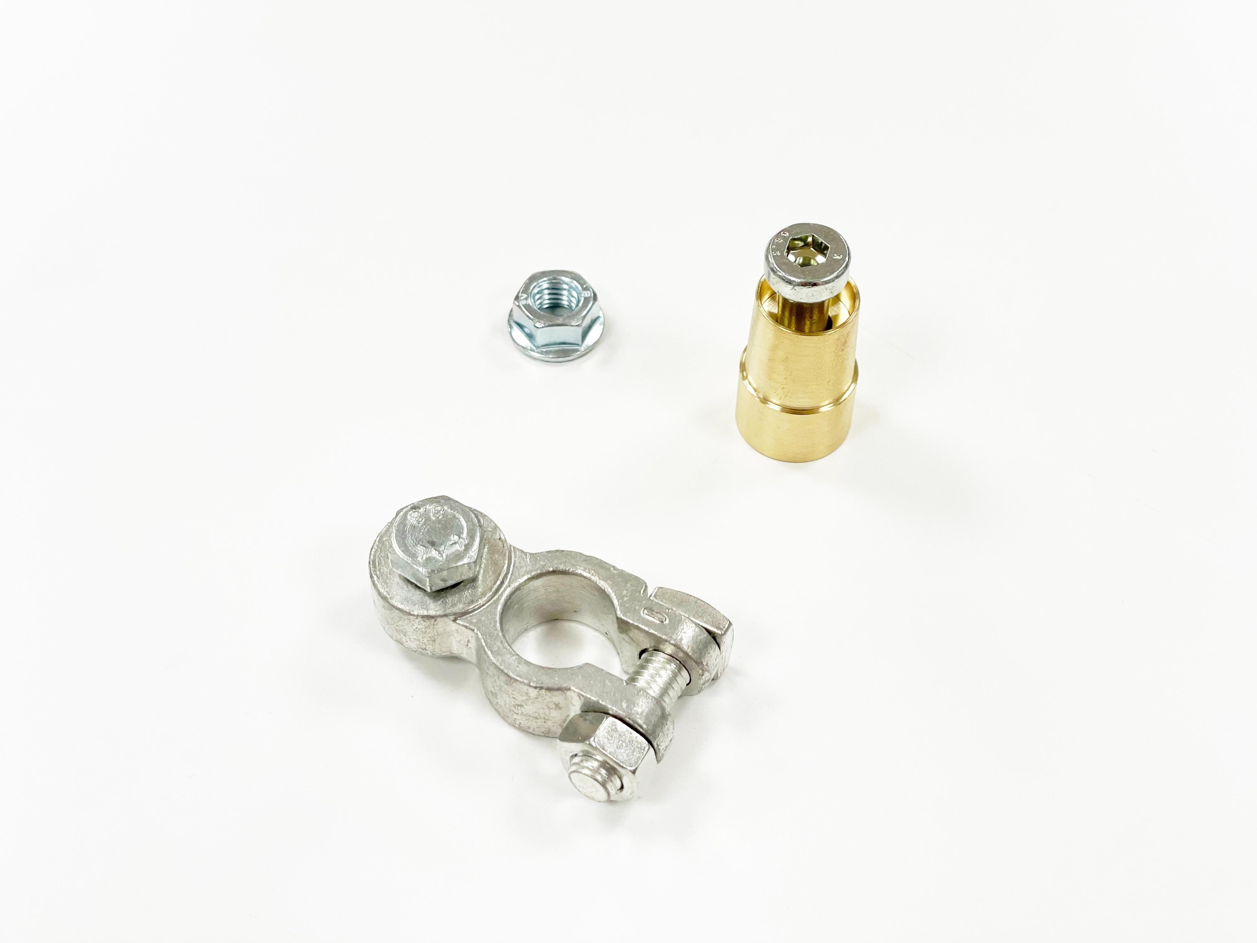 Borne métallique, vis et adaptateur en laiton sur fond blanc.