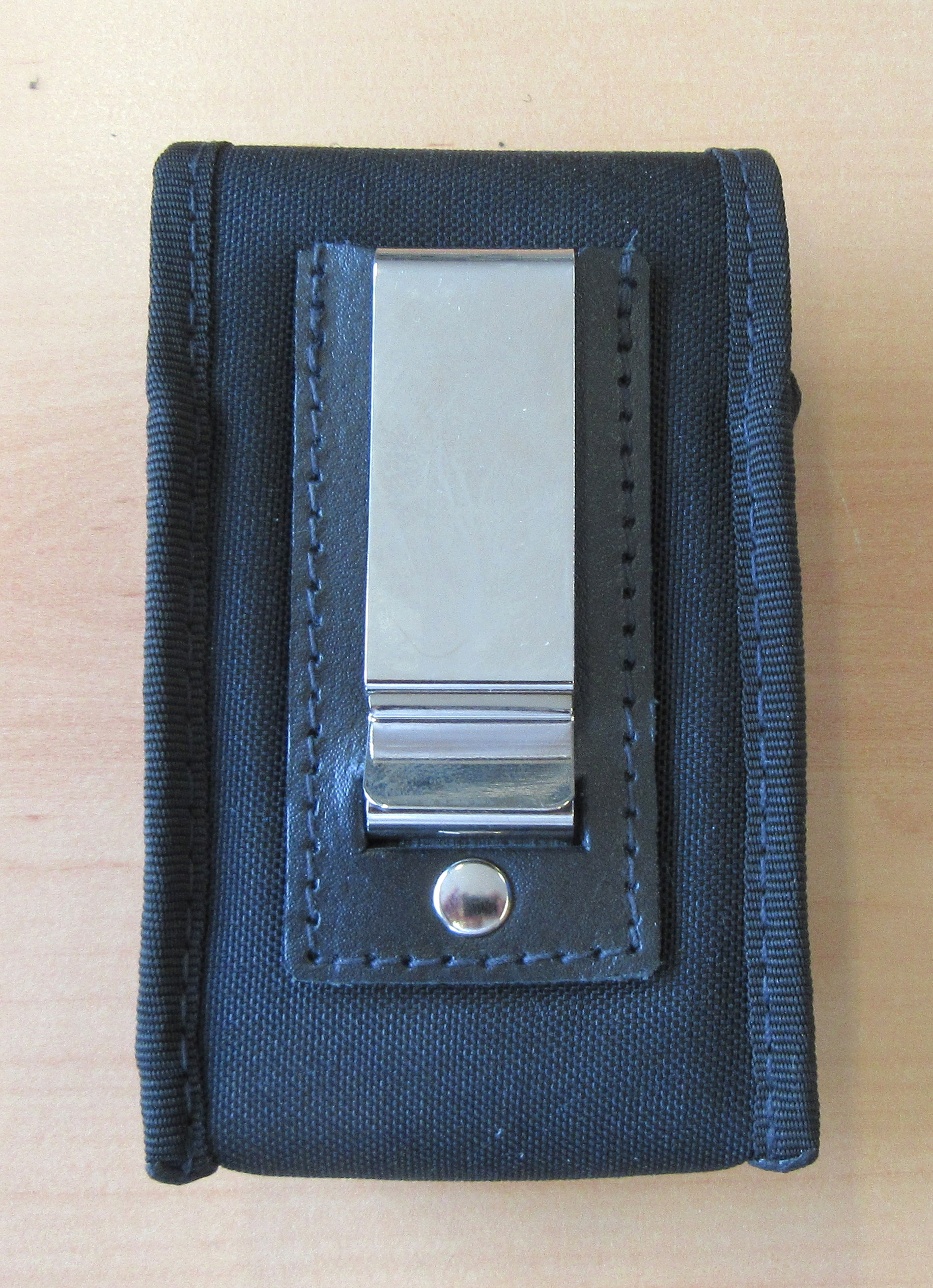 Zwart stoffen zakje met metalen clip op houten tafel.