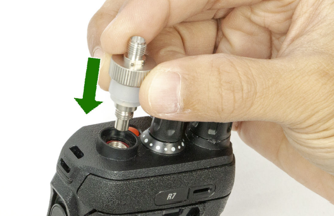 Main fixant un adaptateur sur radio avec flèche verte vers la prise.