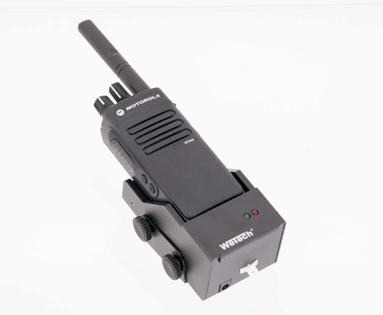 Zwarte walkietalkie met antenne en twee knoppen op laadstation.