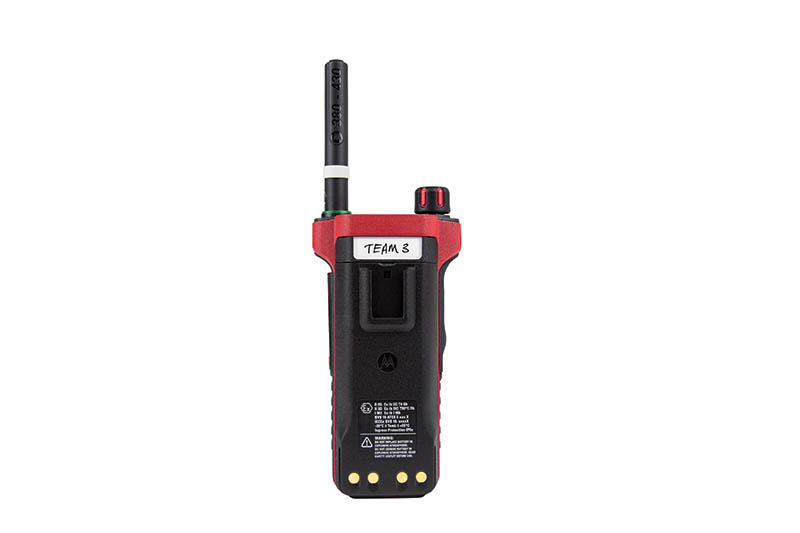 7000-00469500_mot_05.jpg Achterkant van radio met rode rand, sticker 'TEAM 3'.