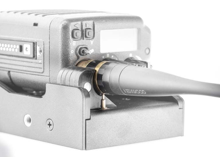 Electronic device with cable connected, mounted on bracket, display and buttons visible.