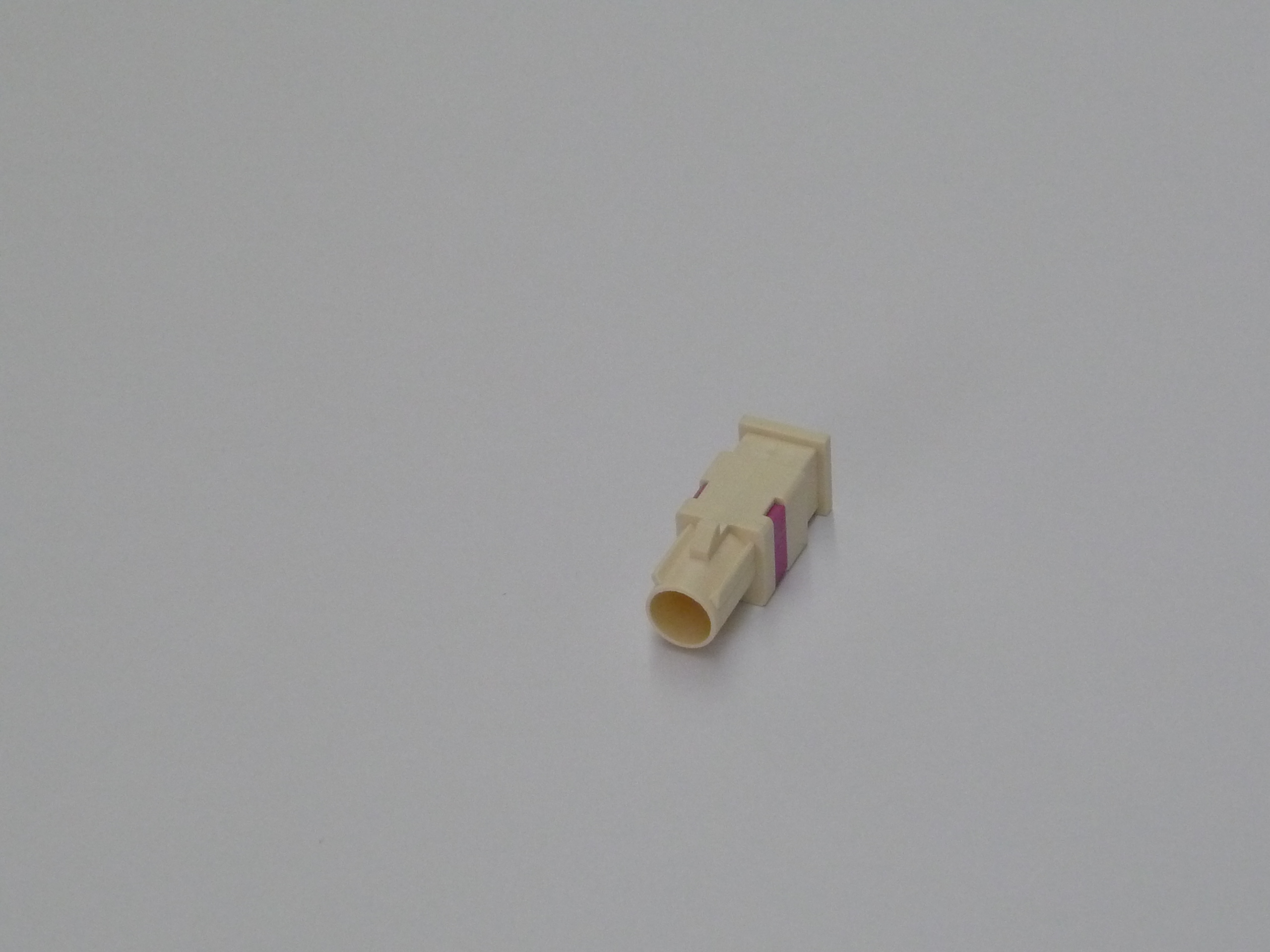 Beige kunststof connector met roze details op witte achtergrond.