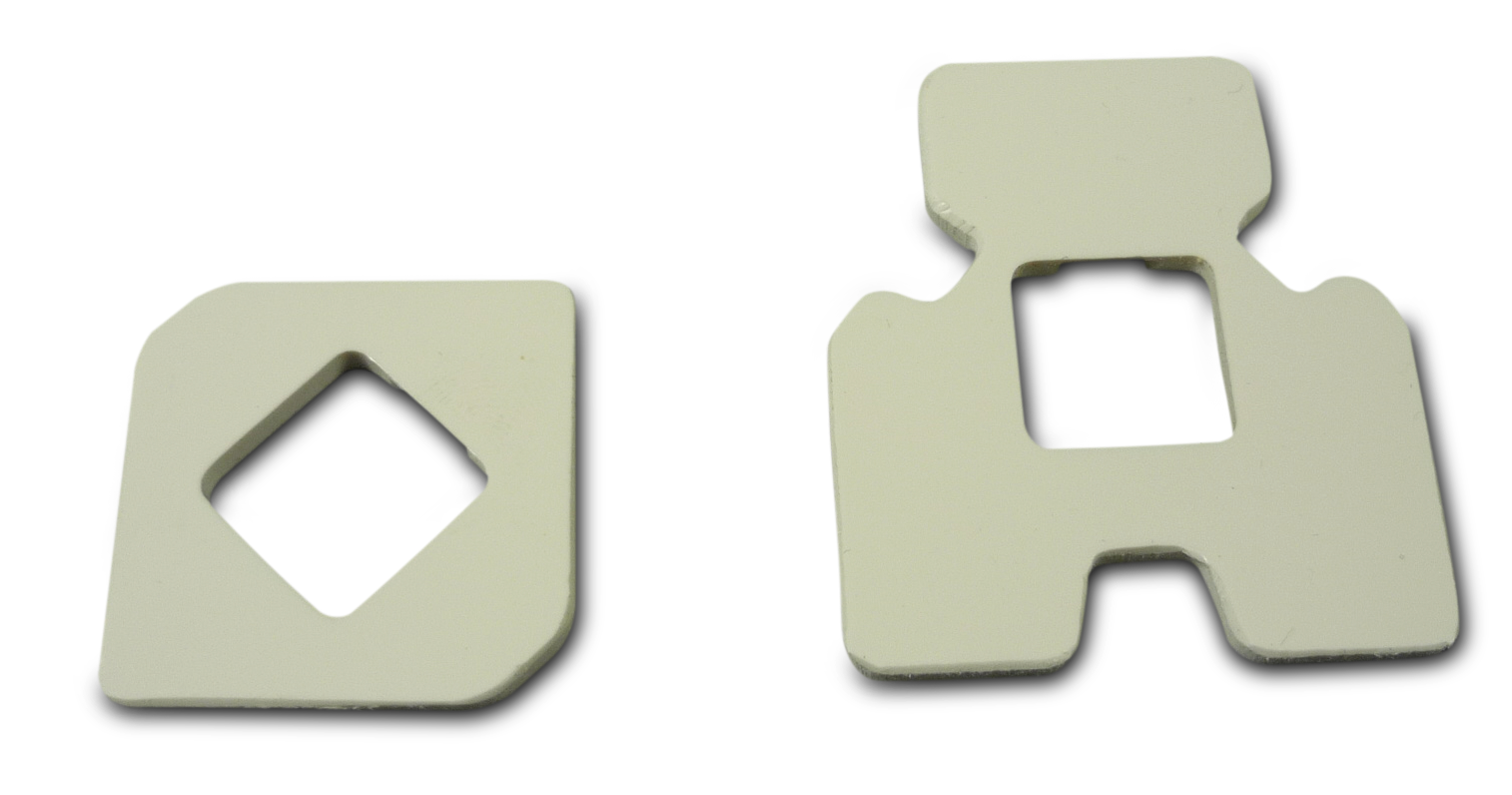 Twee witte plastic stukken met verschillende vormen en uitsparingen.