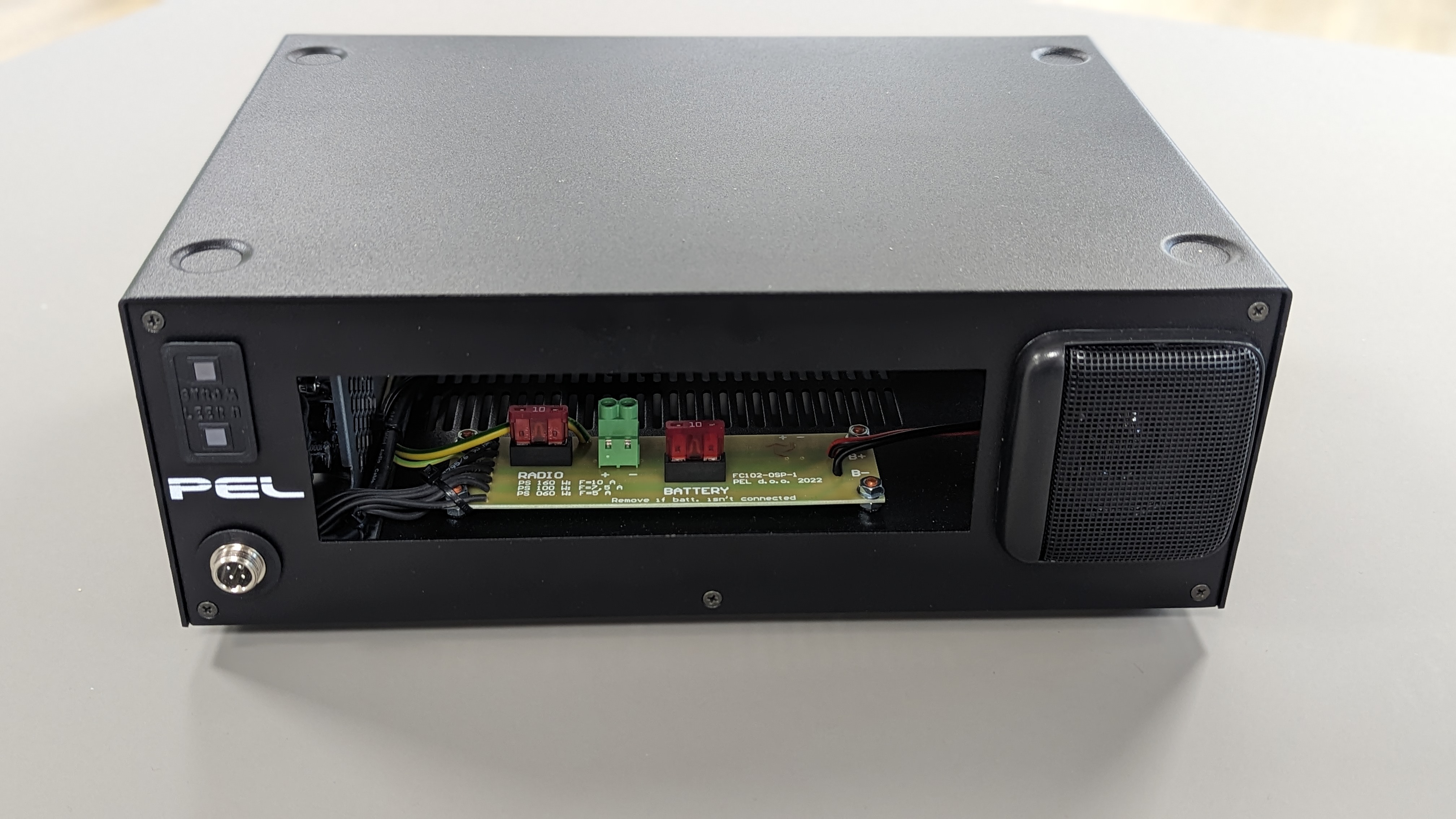 Elektronisch apparaat in zwarte behuizing met open compartiment en zichtbare kabels.