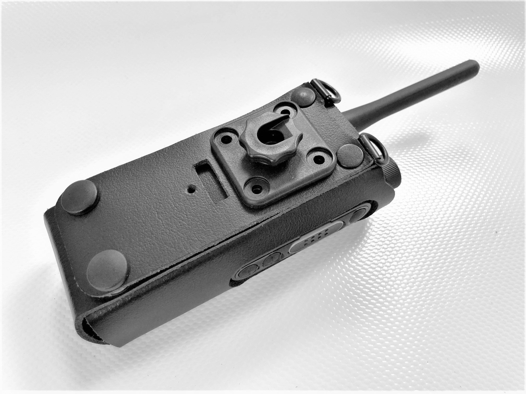 Appareil radio noir dans une housse de protection sur fond blanc.