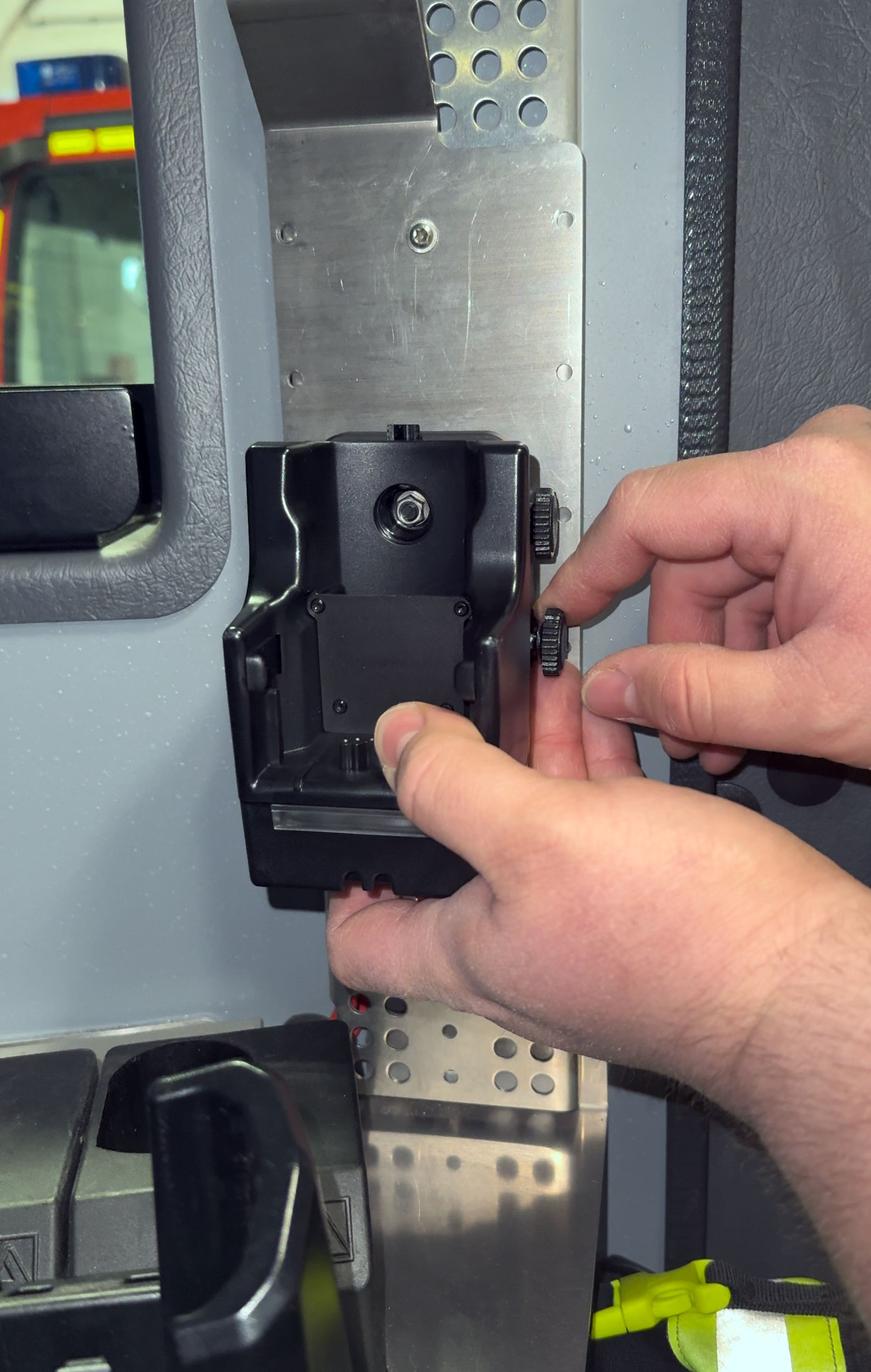 Handen stellen een zwart elektronisch apparaat af op een metalen plaat binnen.
