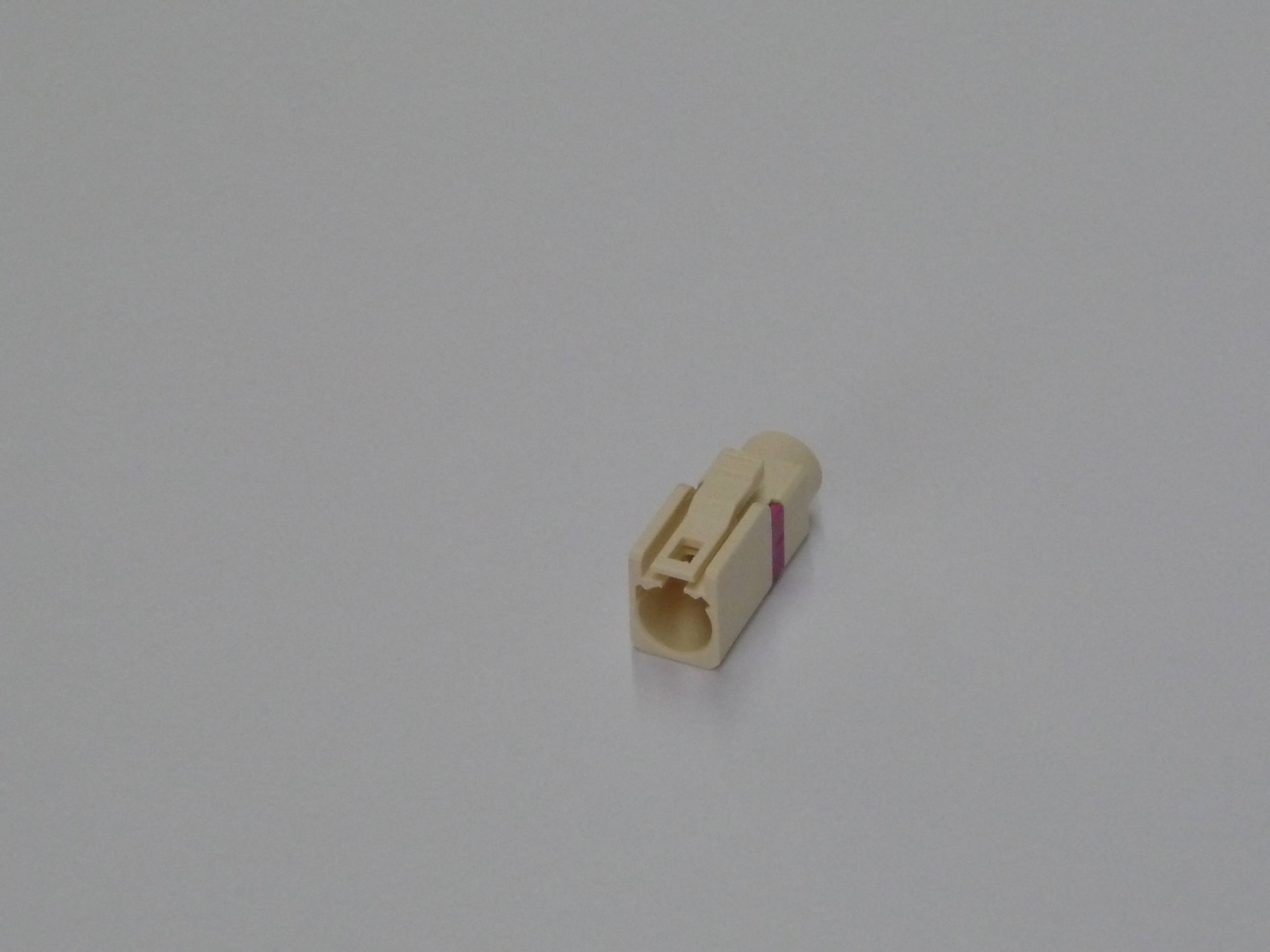 Connecteur en plastique avec marquages rouges sur fond gris clair