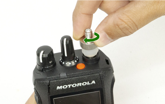 Hand twisting antenna onto Motorola radio.