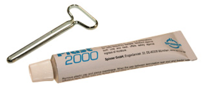 Metalen sleutel en tube met blauwe tekst 'Plast 2000'.