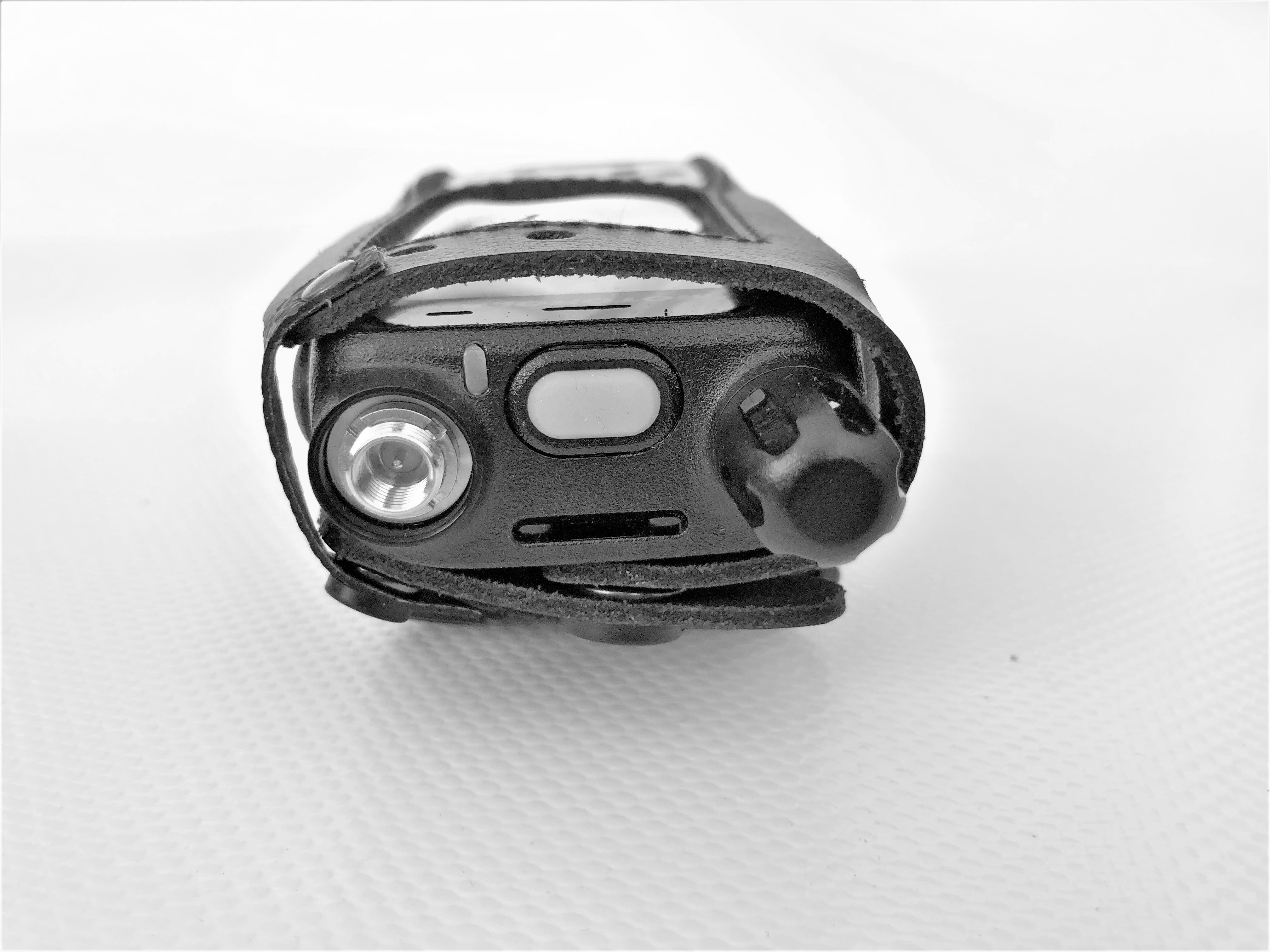 Radio portatif dans un étui en cuir sur une surface blanche.